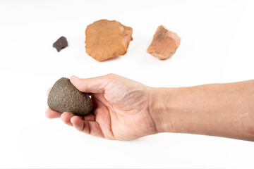 Hand holding polished Neolithic stone axe with Paleolithic biface, knife and arrowhead in background found in Algerian Sahara
