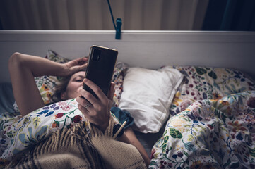 Woman Using Smartphone in Bed at Night © VSzili
