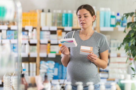 Pregnant woman buys toxicosis pills at a pharmacy. Woman chooses cold pills that can be used by pregnant women