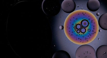 Iridescent oil drops forming rainbow-colored circles and floating on a dark liquid surface.