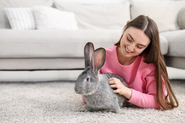 Naklejka premium Woman with cute bunny on floor at home. Space for text