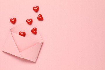 Naklejka premium Love. Envelope with red decorative hearts on pink background, flat lay. Space for text