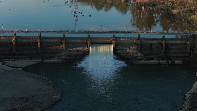 Evening spillway releases water into tranquil lake scene