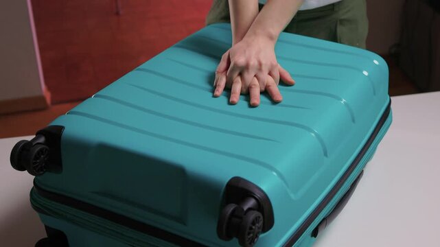 Traveler opening luggage, Close shot of hands unfastening suitcase zipper before travel, Detailed view of hands pulling zipper on vibrant teal travel case with anticipation