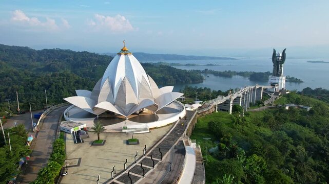 Aerial drone footage of Al Kamil amazing mosque, with lotus flower shape, the main square, the bridge leading to the Kujang tower, at sunset, with Jatigede reservoir behind, in Sumedang, Indonesia