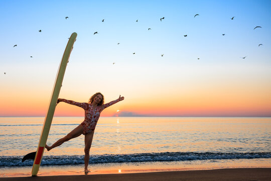 Young woman standing on beach with paddle sup boards during summer vacation