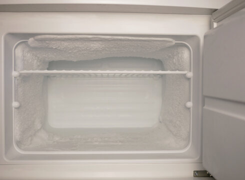 Empty freezer with heavy frost and ice buildup. Cold storage concept, refrigeration problem, defrost need, appliance maintenance, food safety, copy space