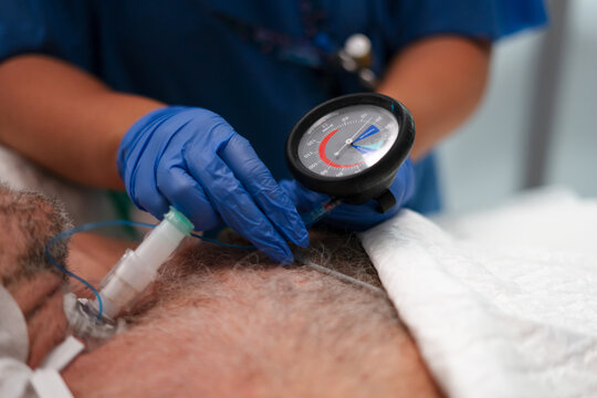 Nurse checking cuff pressure of a tracheostomy tube on patient