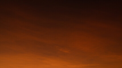 Deep dark amber and orange sunset sky texture with subtle clouds and smooth gradient