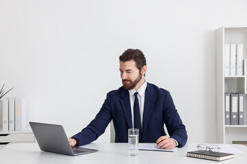 Fototapeta premium Businessman working with laptop at table near white wall indoors