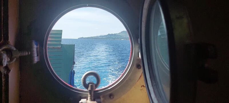 view of the crashing waves of the ship seen from the round ship window 