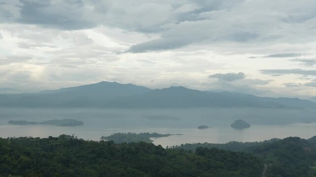 Cinematic timelapse of moving clouds over Jatigede Lake and mountain ranges in Sumedang during a moody morning.