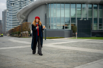 Young woman walking city street checking smartphone