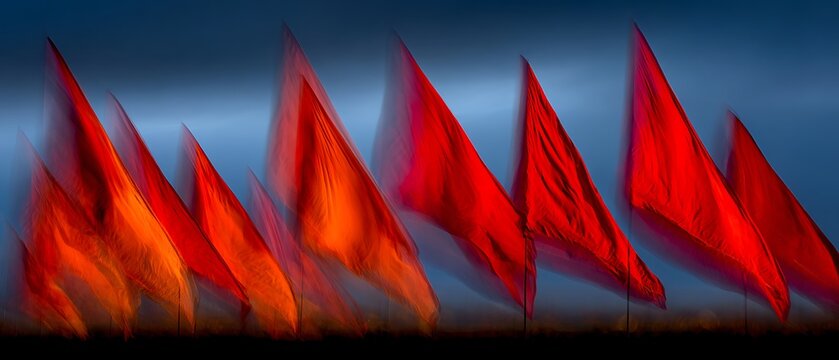 Vibrant red flags waving dramatically against a dark blue sky