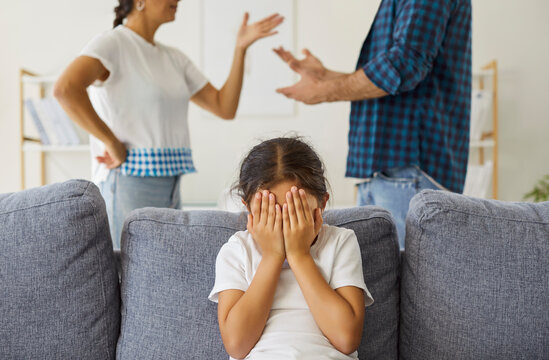 Kids hands hide face amid parental conflict and fight at home. Angry father and mothers arguments and quarrel in living room, sad daughter with stress and trauma crying because of domestic violence