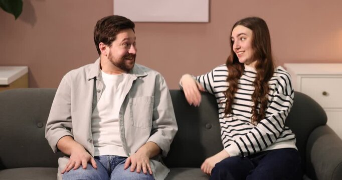 Bad date. Embarrassed man talking with woman on sofa at home. Camera moving down