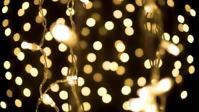 Blurred string lights create a warm and festive atmosphere against a dark background, perfect for holiday decorations.