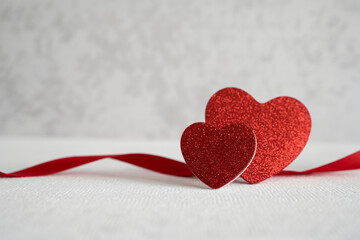 Two sparkling red glitter hearts stand beside a vibrant satin ribbon centerpiece decoration.