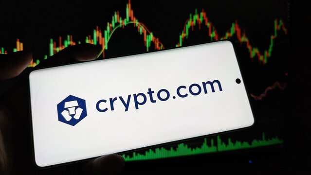 Crypto.com logo on smartphone screen with stock market graph background