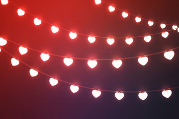 Hanging heart string lights on red background. Romantic love festive decoration.