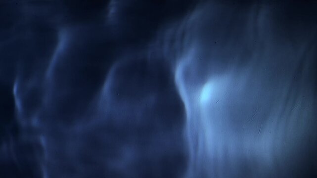 Pool water ripples at night in dim light dark swimming pool background