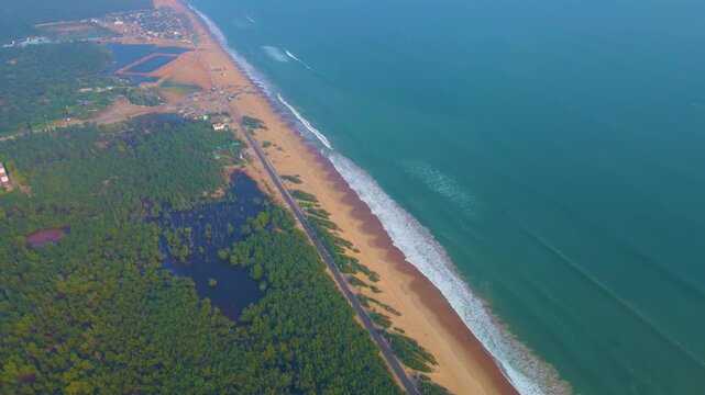 Scenic aerial view of Puri Konark Marine Drive coastline, Odisha, India, with wide sandy beach, turquoise ocean, palm-lined shore, and natural tropical seascape