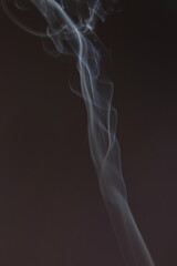 Obraz premium Blue smooth texture smoke from incense aroma stick in motion rising above in holiday celebration with empty copy space dark background. Yoga calm meditation, relaxation concept 