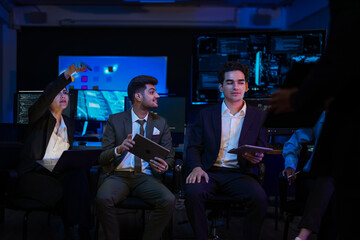 Innovative tech team discussing project. Professional leader pointing at screen while colleagues analyze data in modern blue night office. Business executives with tablet planning investment strategy.