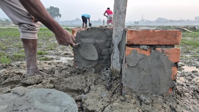 Professional cinematic video of construction of a brick boundary pillar in a paddy field, Agriculture & Land Management in Bangladesh, 4K UHD 30fps.