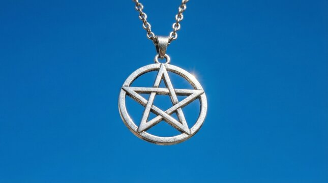 Close-up of pentacle pendant against blue sky