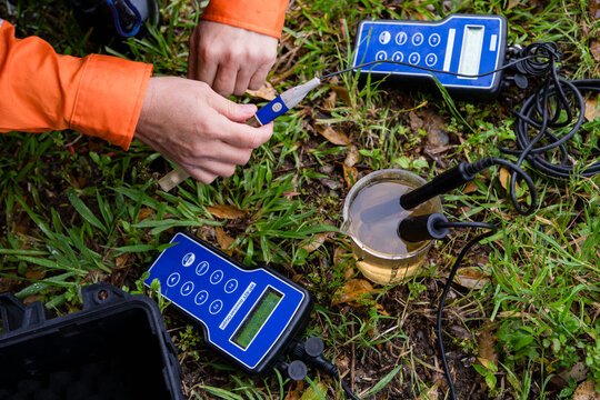 A field technician taking and testing a water sample with equipment - horizontal