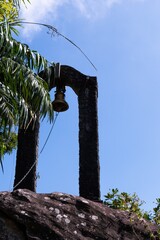 Historic stone bell tower against a vibrant blue sky surrounded by lush greenery.