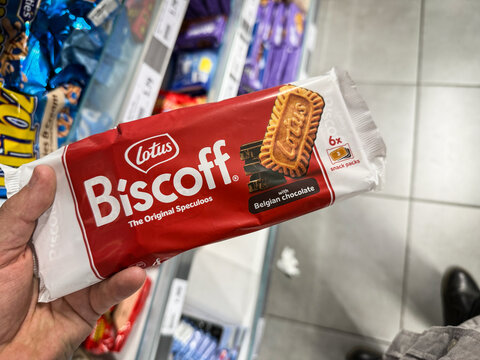BELGRADE, SERBIA - AUGUST 10, 2025: Hand holds a Lotus Biscoff speculoos biscuit pack with Belgian chocolate in a Belgrade supermarket. Speculoos is a traditional belgian cookie and biscuit.