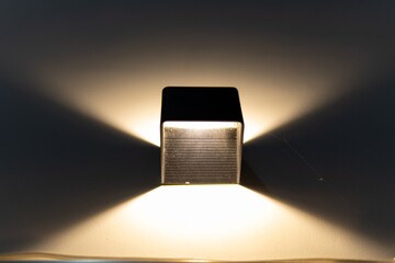 Modern black cube light fixture casting a warm, symmetric glow.