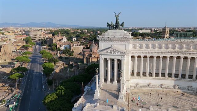 Aerial drone view along Via dei Fori Imperiali with Vittoriano monument, traffic road, ancient forums and dense Rome Italy, cityscape in warm sunlight. clear summer atmosphere daylight. Pizza Venezia