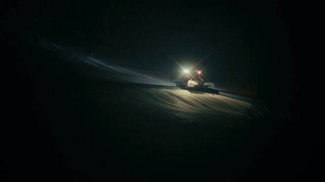 Ski Resort Maintenance at Night &ndash; Snow groomer shaping slopes before morning skiers arrive.