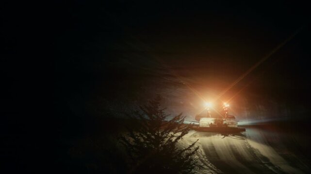 Snow Groomer at Night &ndash; Snow grooming machine preparing ski slopes under dark night sky.