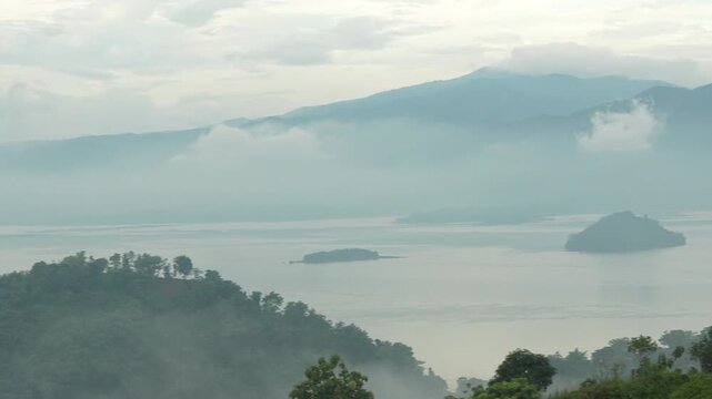 Morning Panoramic view of Jatigede reservoir featuring small islands and lush green forests under a cloudy sky in West Java, Indonesia