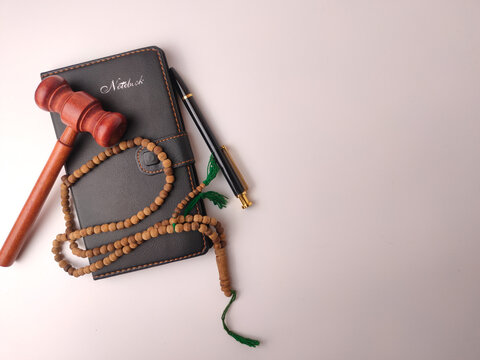 Wooden gavel, prayer beads (tasbih), and a notebook,represent the concept of Islamic law or Sharia