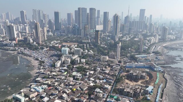 Drone aerial of Mumbai highlighting sharp contrast between informal coastal housing and modern high-rise skyline. Concept of social inequality, urban expansion and megacity growth.