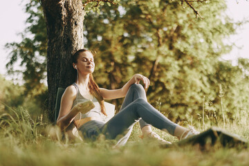 Obraz premium Young woman enjoying a healthy snack outdoors in a sunlit park, surrounded by greenery, conveying a sense of relaxation and well being in a seasonal setting