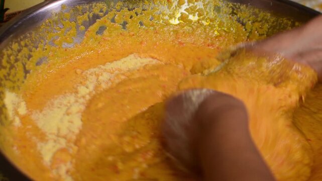 Unique culinary traditions. Hands mixing yellow cornmeal with water and annatto (onoto) oil, adding extra flour to reach the perfect consistency for Latin American recipes.
