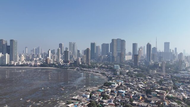 Worli Village, Mumbai, India &ndash; January 25, 2026. Lateral movement across historic fishing settlement on the coastline with exposed seabed at low tide and modern Mumbai skyscrapers in the background