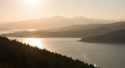 Fototapeta premium Golden sun reflecting on lake, with distant mountains and forest in foreground