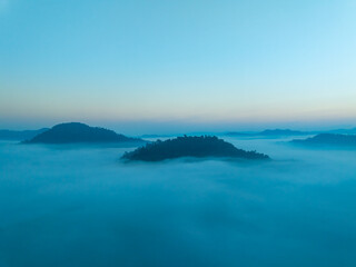 Aerial view of flowing fog waves on mountain tropical rainforest,Bird eye view image over the clouds Amazing nature background with clouds and mountain peaks in Thailand