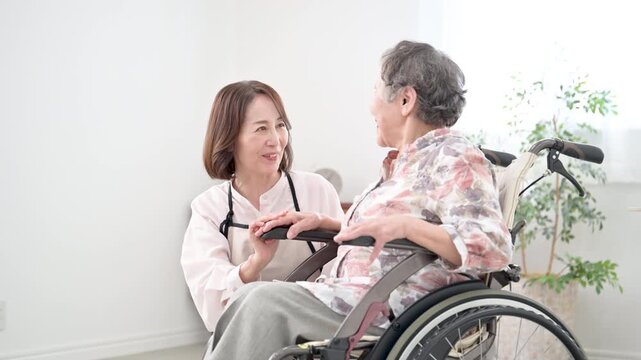 自宅で車椅子の母を介護をする様子　見つめ合う在宅介護のイメージの動画