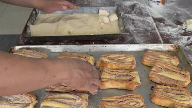 BAKER PLACING SUGAR ON THE SWEET BREAD CALLED BOOK