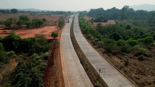 Scenic highway of mumbai goa red soil focused on truck passing ariel view 