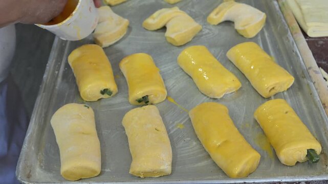  Glazing the sweet bread filled with guava paste with egg wash.