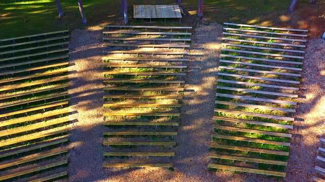 Empty wooden benches set in a natural forest clearing, awaiting an outdoor event